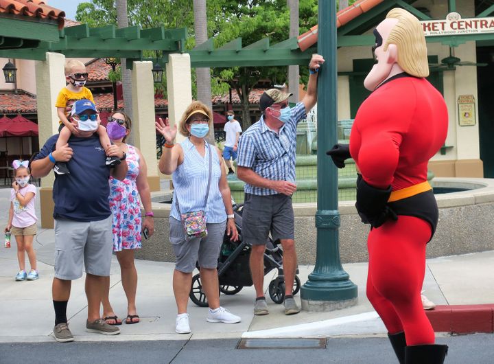 Guests wave to Mr. Incredible during a pop-up appearance of Pixar characters at Disney's Hollywood Studios at Walt Disney World on July 16, the second day of the park's reopening, in Lake Buena Vista, Florida.